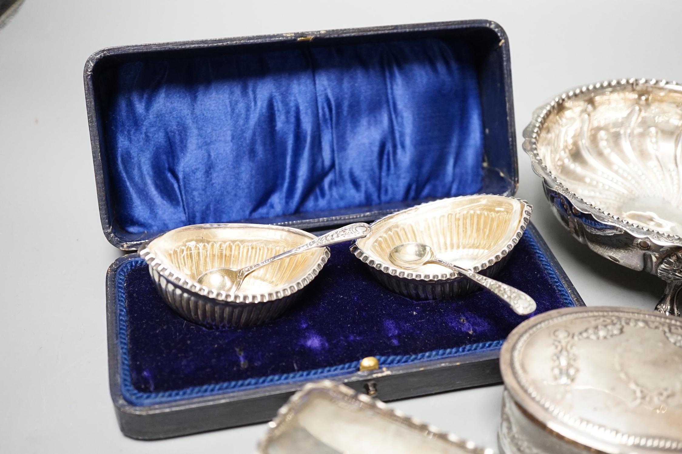 A Victorian repousse silver two handed bowl, one other silver bowl, a silver sifter spoon, four silver mounted glass toilet jars, a silver dwarf candlestick and a cased pair of silver salts.